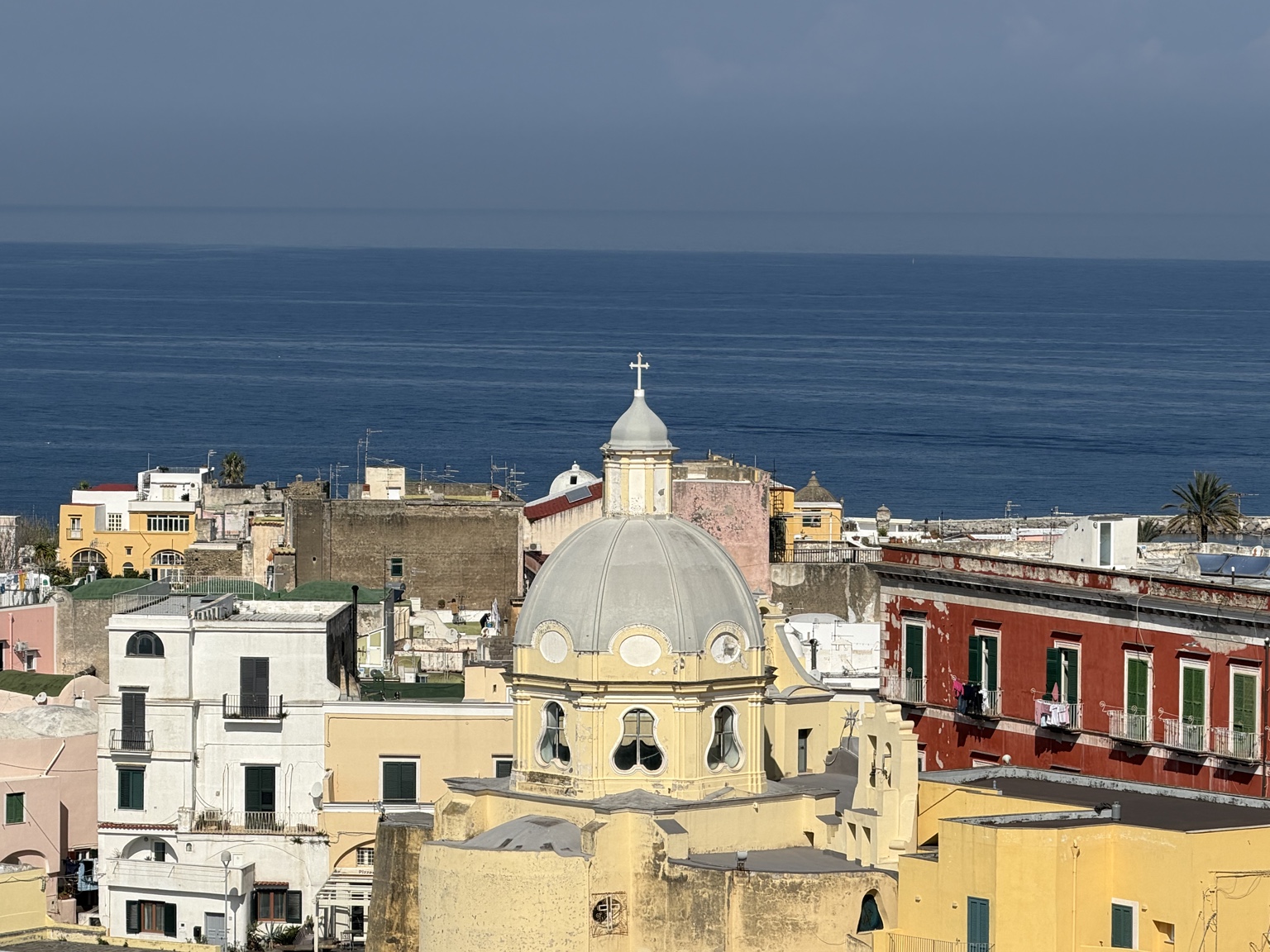 Cupola di una chiesa tra i tetti, con il mare sullo sfondo